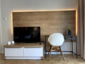 een woonkamer met een witte stoel en een televisie bij Acapella Suite Adagio 54qm, direkt am Weinberg, Altstadt, Netflix inklusive in Heppenheim an der Bergstrasse