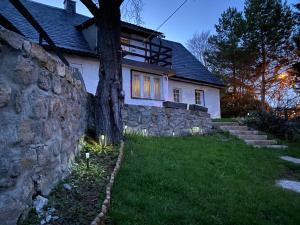 a house with a stone wall next to a tree at Domek z duszą in Szklarska Poręba