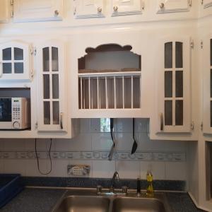 a kitchen with white cabinets and a sink at The Braemar Suite III New Kingston in Kingston