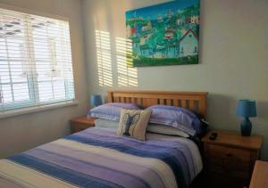 a bedroom with a bed and a painting on the wall at Seven Bays Stays in St Merryn