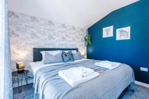 a blue bedroom with a bed with towels on it at Rest&Recharge at Ridgefield House (5 Bedrooms, 8 Beds, 2 Bathrooms, Free parking) in Manchester