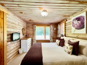 Dormitorio en cabaña de madera con cama y TV en Lindley Log Cabin en Lincoln