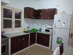 a kitchen with wooden cabinets and a white refrigerator at Santos`s House in São Tomé