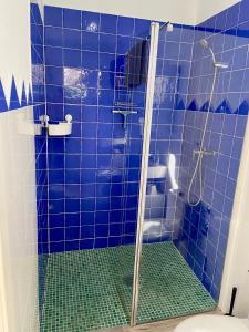 y baño de azulejos azules con ducha y aseo. en Casa La Parra, 64 en Nerja