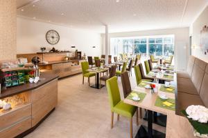 un restaurante con mesas de madera y sillas verdes en Landhotel Behre, en Lehrte