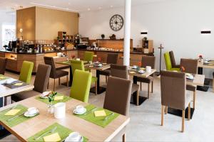 um restaurante com mesas de madeira e cadeiras verdes em Landhotel Behre em Lehrte