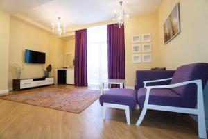 salon z fioletowymi krzesłami i telewizorem w obiekcie ILK INN HOTEL w mieście Qusar