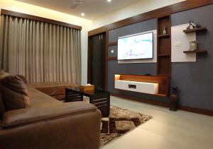 a living room with a couch and a flat screen tv at Feliz Homes Kottakkal in Kottakkal