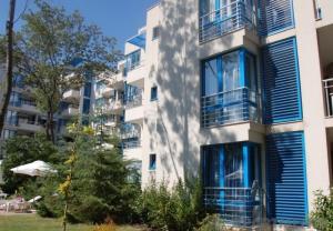 Private apartments Aparthotel Excelsior في ساني بيتش: مبنى طويل وبه شرفات زرقاء على جانبه