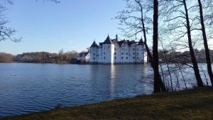 un grand château blanc au sommet d'un lac dans l'établissement Ferienappartment am Kurpark. 100m zum Strand., à Ulstrupfeld
