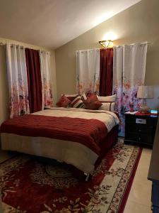 a bedroom with a large bed with red curtains at Luxury Manor 2 Bedroom /1 Bathroom House w/electric fireplace, in Montego Bay
