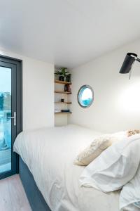 a white bedroom with a bed and a window at Lemuria Houseboat - pływający domek na wodzie in Wrocław