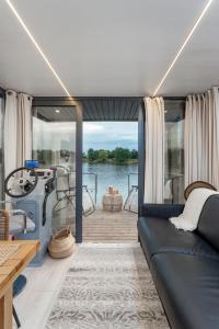 a living room with a couch and a boat on the water at Lemuria Houseboat - pływający domek na wodzie in Wrocław