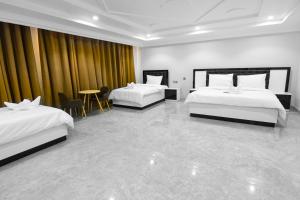 una camera d'albergo con due letti e un tavolo di عبري كاسل هوتيل a Ibri