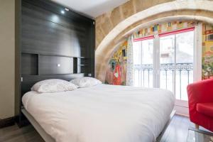 Un dormitorio con una gran cama blanca y una ventana en Apparts en ville Place de la Bourse, en Burdeos