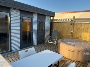 a patio with a hot tub and a chair on a deck at Adorable Tiny House in Reykjavik in Gufunes