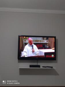 een televisiescherm met een man met een microfoon bij Pousada Quarto com ventilador,ar frigobar e garagem in Aparecida