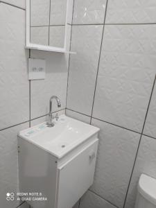 a white bathroom with a sink and a toilet at Pousada Quarto com ventilador,ar frigobar e garagem in Aparecida