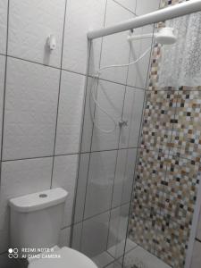 a bathroom with a toilet and a glass shower at Pousada Quarto com ventilador,ar frigobar e garagem in Aparecida