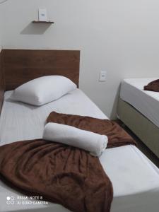 a bed with two towels sitting on top of it at Pousada Quarto com ventilador,ar frigobar e garagem in Aparecida