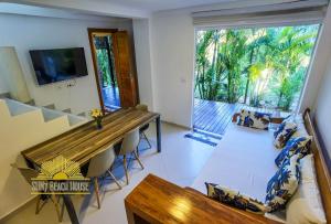 a living room with a wooden table and a large window at SUN7 in Morro de São Paulo