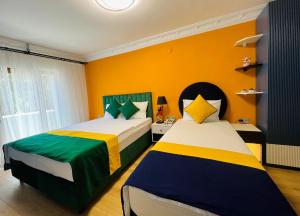 two beds in a room with yellow walls at Apex Hotel in Istanbul