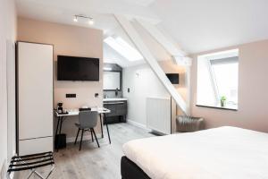 a bedroom with a bed and a desk and a tv at L'ARTiste in Lessines