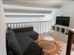 een woonkamer met een bank en een flatscreen-tv bij Duplex terrasse vue mer accès plage et piscine... in Frontignan