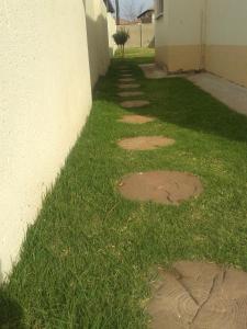a grassy sidewalk next to a building with a wall at Turquoise View Guesthouse in Middelburg
