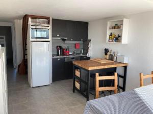 een keuken met een witte koelkast en een tafel bij Duplex terrasse vue mer accès plage et piscine... in Frontignan