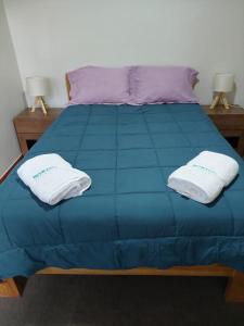Una cama azul con dos almohadas blancas. en Benkawasi Experience Huaraz, en Huaraz