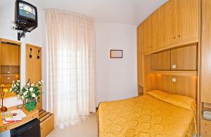 1 dormitorio con cama amarilla y TV en Hotel Bianchi, en Bibione