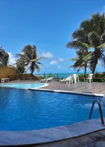 a swimming pool with palm trees and the ocean at atlantico flat 01 in Natal
