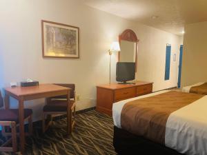 um quarto de hotel com uma cama, uma secretária e uma televisão em America's Best Value Inn em Sandpoint