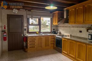 cocina con armarios de madera, fregadero y ventana en Tu casa en el Fin del Mundo en Ushuaia