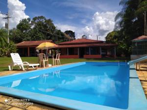 a pool with chairs and a house in the background at chácara solar das águas in Socorro