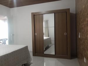a bedroom with a wooden cabinet with a mirror at Apartamento com suíte, localizado na Avenida Silvio Silva, n 33, bairro Hernani Sa, Ilhéus - Ba, sem garagem in Ilhéus