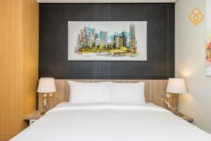a bedroom with a bed and a painting of a city at Modern Beach Studio Murjan 5, 22B in Dubai