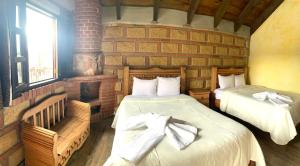 a bedroom with two beds and a brick wall at Hotel La Condesa in Huasca de Ocampo