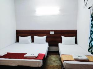 two beds in a room with white walls at Royal Green Residency Chennai Airport in Chennai