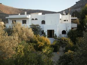 a white house with trees in front of it at Hotel Narkissos in Archangelos