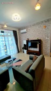 a living room with a couch and a flat screen tv at J&J Vacation Home@Novo8 Residence in Kampong Tambak