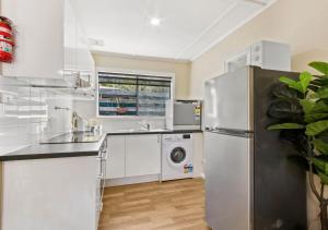 a kitchen with a refrigerator and a washing machine at Metung Akora 2Bdrm Apartment 1 - Pets & Boats welcome! Close to Town, Free Wifi & Netflix in Metung