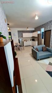 a living room with a blue couch and a kitchen at J&J Vacation Home@Novo8 Residence in Kampong Tambak
