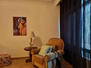 a living room with a chair and a painting at Su's AlKursi Cozy Apartment in Amman