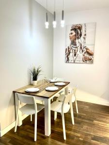 een eettafel met witte stoelen en een schilderij bij SEA APART in Gdańsk