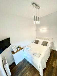 een slaapkamer met een wit bed en een televisie bij SEA APART in Gdańsk
