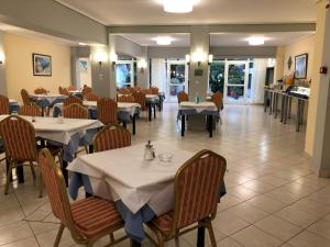 a restaurant with tables and chairs with white tables at Hotel Bakos in Loutraki