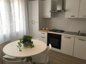 a white kitchen with a white table and a stove at Chioggia House di Marco in Chioggia