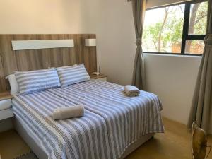 a bedroom with a bed with a striped blanket and a window at Vlakkieskraal Farmstay - BushBaby House in Bela-Bela